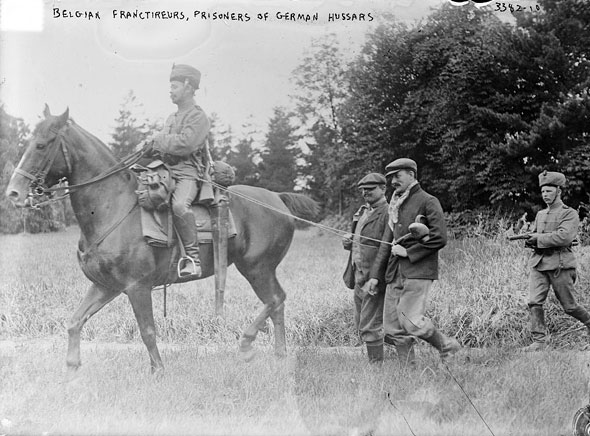 Belgian civilians, suspected by German cavalrymen of partisans, are brought to headquarters to face possible execution. 