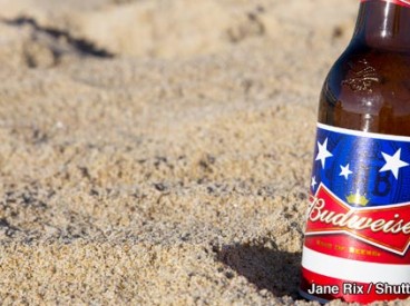 A bottle of Budweiser in the sand