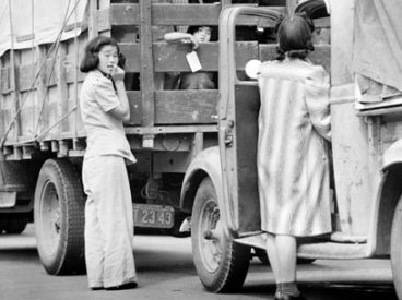 Japanese-American residents loading household belongings onto trucks.