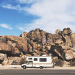 An RV driving down a desert road.
