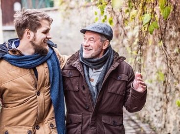 A grandfather walks with his adult grandson down a street.