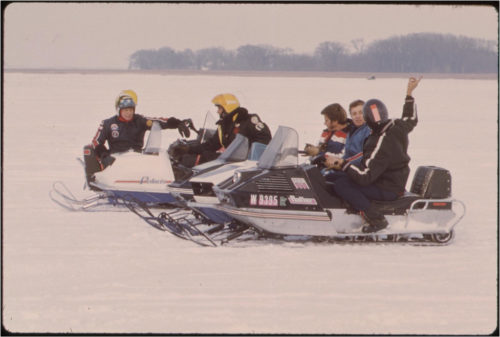 People driving snowmobiles