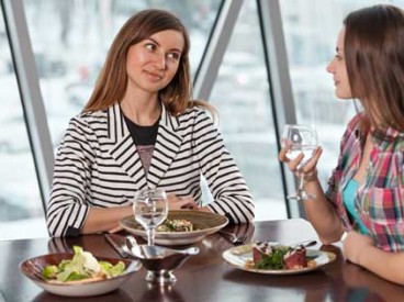 Two women talking at lunch. Source: Shutterstock.com/Evstigneev Alexander