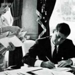 President Kennedy signs documents in the Oval Office. © SEPS 2013
