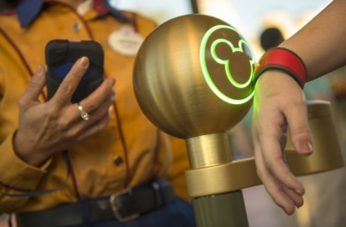 An Disney World guest holds a wrist band to a Mickey Mouse icon.