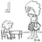 A school student talks to his teacher in a classroom.