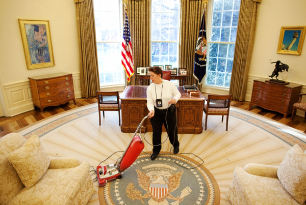 A worker vacuums pine needles after a Christmas tree was removed from the Oval Office, December 30, 2009. Norman Rockwell's "Working on the Statue of Liberty" can be seen hanging to the right of the president's desk. (Official White House Photo by Chuck Kennedy)