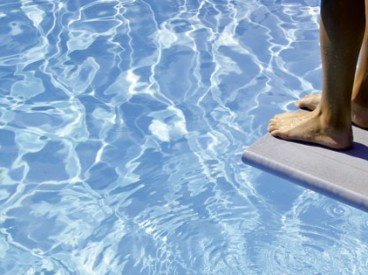 feet on diving board over pool