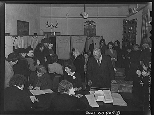 Arlington, Virginia. Interior of the firehouse with firemen's trophies in the background. Citizens' names are checked to see that each has paid his poll tax and registered. Ballots for the national presidential election are presented to each for secret voting in the "Douglas Collapsible" booths, and the ballots are dropped in boxes. Source: Library of Congress Prints and Photographs Division, Washington DC.