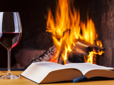 book and full wineglass in front of fireplace