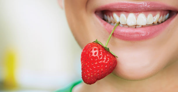  strawberry between her teeth by its stem. Source: Shutterstock.com