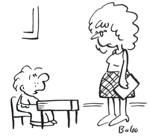 A student talks to his teacher at his desk.