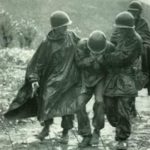 Korea 1950: An exhausted soldier is evacuated by Capt. Jerome Dolan and Chaplain Kaplaun.