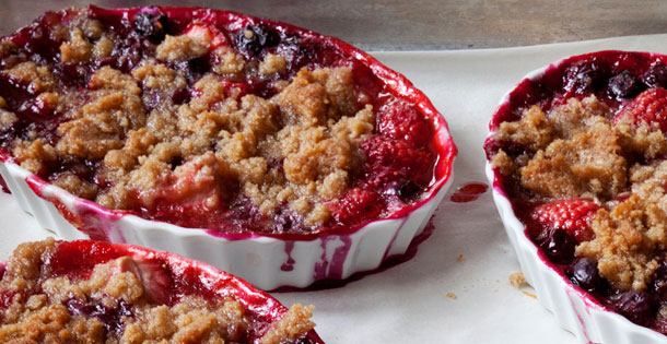 berry crumble desserts in creme brulee dishes on oven sheet
