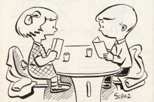 Two children talk at a table.