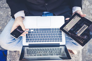 man using a laptop, a tablet, and a smartphone at once