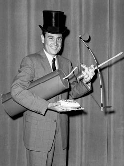 Bob Barker with a pie and a oversized stick of dynamite.