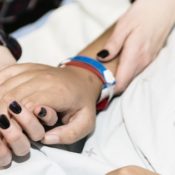 A woman holder her dying parent's hand