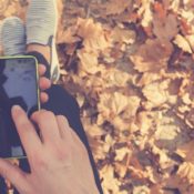Man holding a smart phone over a floor of autumn leaves