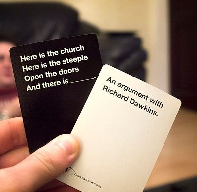A player holds two cards from the game, "Cards Against Humanity."