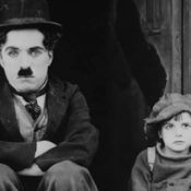 Charlie Chaplin sitting next to a newsboy