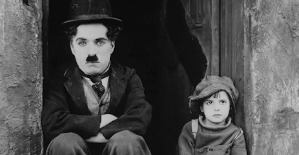 Charlie Chaplin sitting next to a newsboy