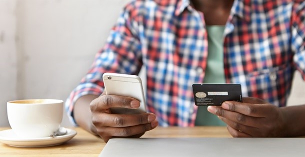 Man holding credit card while shopping on his smart phone