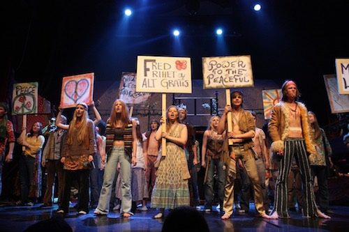 Hair production. Actors on stage with protest signs