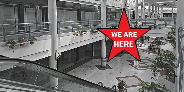 The interior of an abandoned mall. A star with the message "We Are Here" is superimposed over it