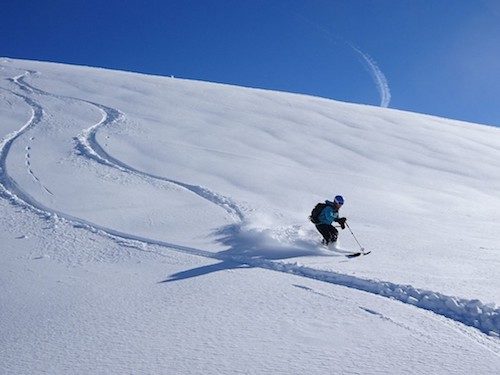 A skier moving down a mountain side