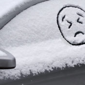 A sad emoji traced on a snow-covered car window