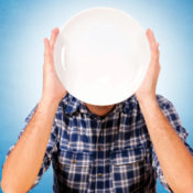 Man holding plate in front of his face