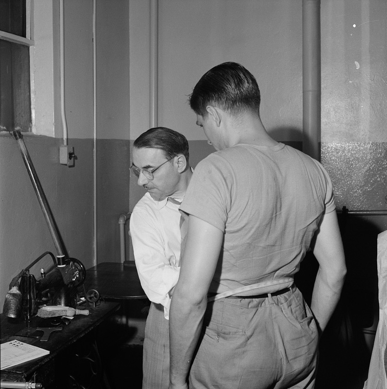 A tailor fitting a coat at the shop maintained in the Greyhound garage. Drivers pay a dollar a month and can have clothes altered, fitted, and pressed at any time.