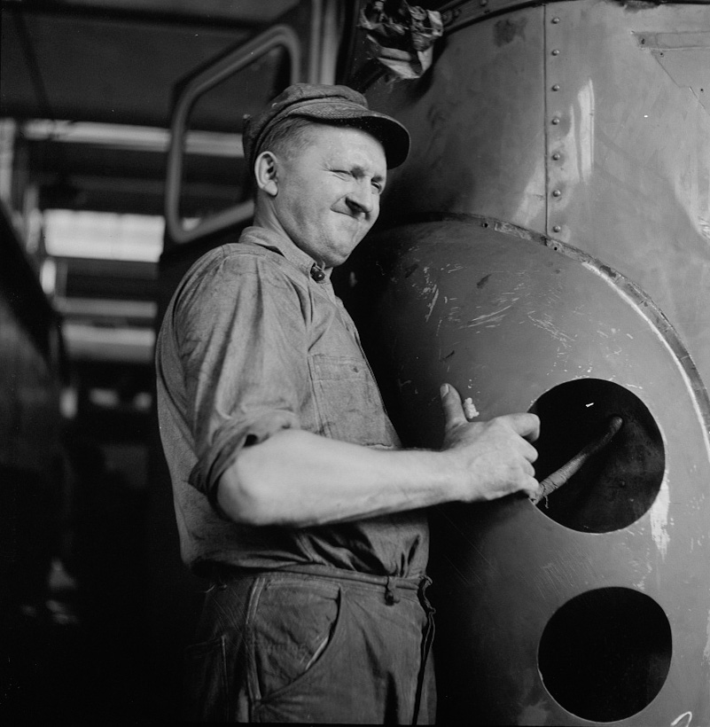 A mechanic straightening a bent fender on a bus at the Greyhound garage, 