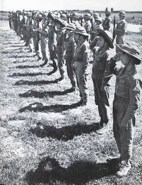 Teenage South Vietnamese girls in military uniform stand at attention at their defense post.