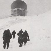 Men walking to a radar attenae in the snow