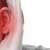 Woman holding her hand to her ear, signifying hearing loss.