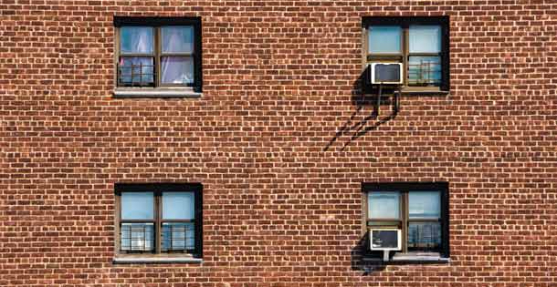 A set of windows in the brick wall of an apartment building.