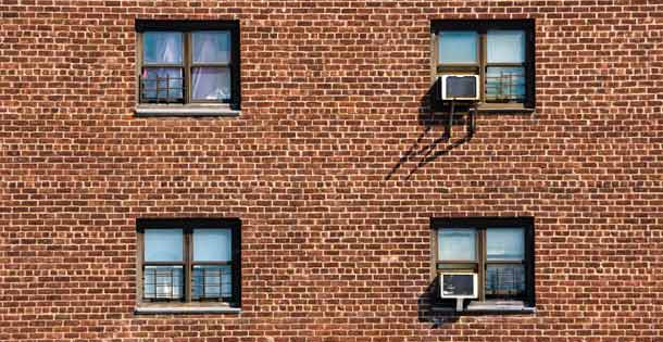 A set of windows in the brick wall of an apartment building.