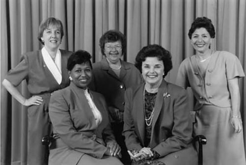 Senators Murray, Mikulski, Boxer, Braun, and Feinstein sit together for a 1992 photo. They are wearing pants in defiance of the Senate's dress code for women.