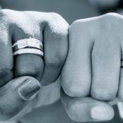 Two hands with wedding rings fist bump.