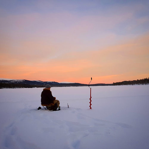 An ice fisher with his lure in the ice.