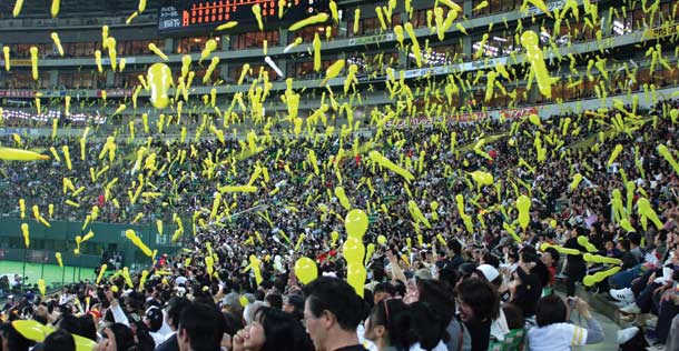 Japanese people play with balloons in a baseball stadium