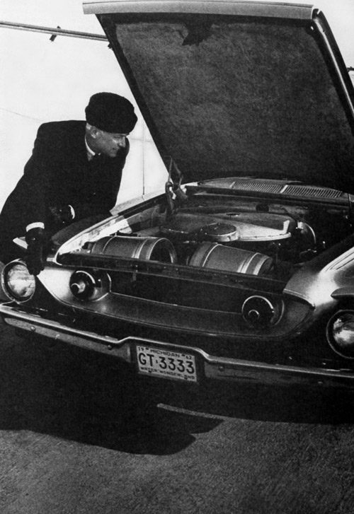 George Huebner looks under the hood of a car.