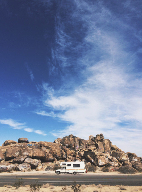 An RV driving down a desert road.