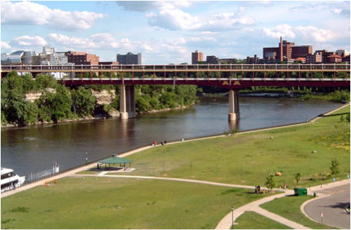 Image of the Washington Avenue bridge, overlooking the river and a green lawn.