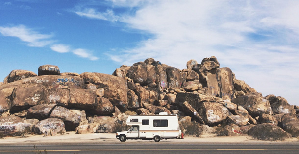 An RV driving down a desert road.