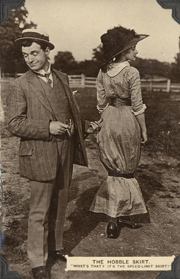 A man looking away from a woman, who's wearing a dress that has a loose-fitting belt around her shins.