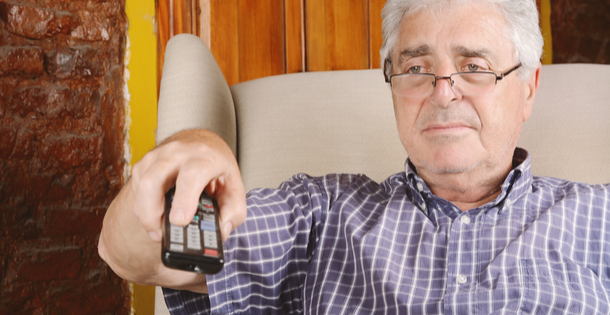 Older man flipping through television channels with his remote.
