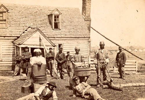 Escaped slaves and Union sympathizers pose for the camera in front of a house.